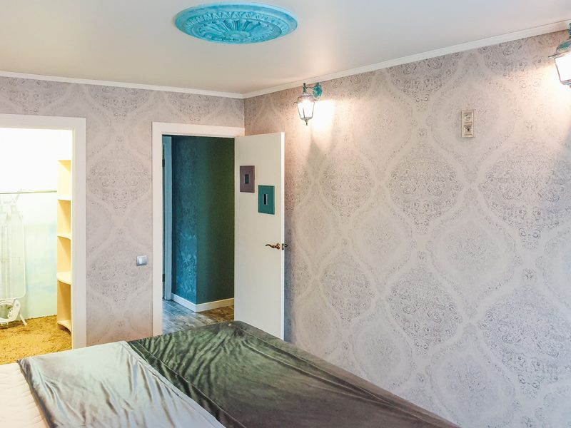 Bright modern bedroom with a soft grey damask wallpaper wrapping the walls behind the bed