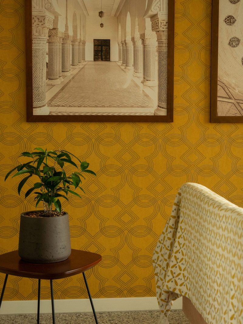 Sitting area with a warm golden honeycomb-patterned accent wall, potted plants, and framed artwork