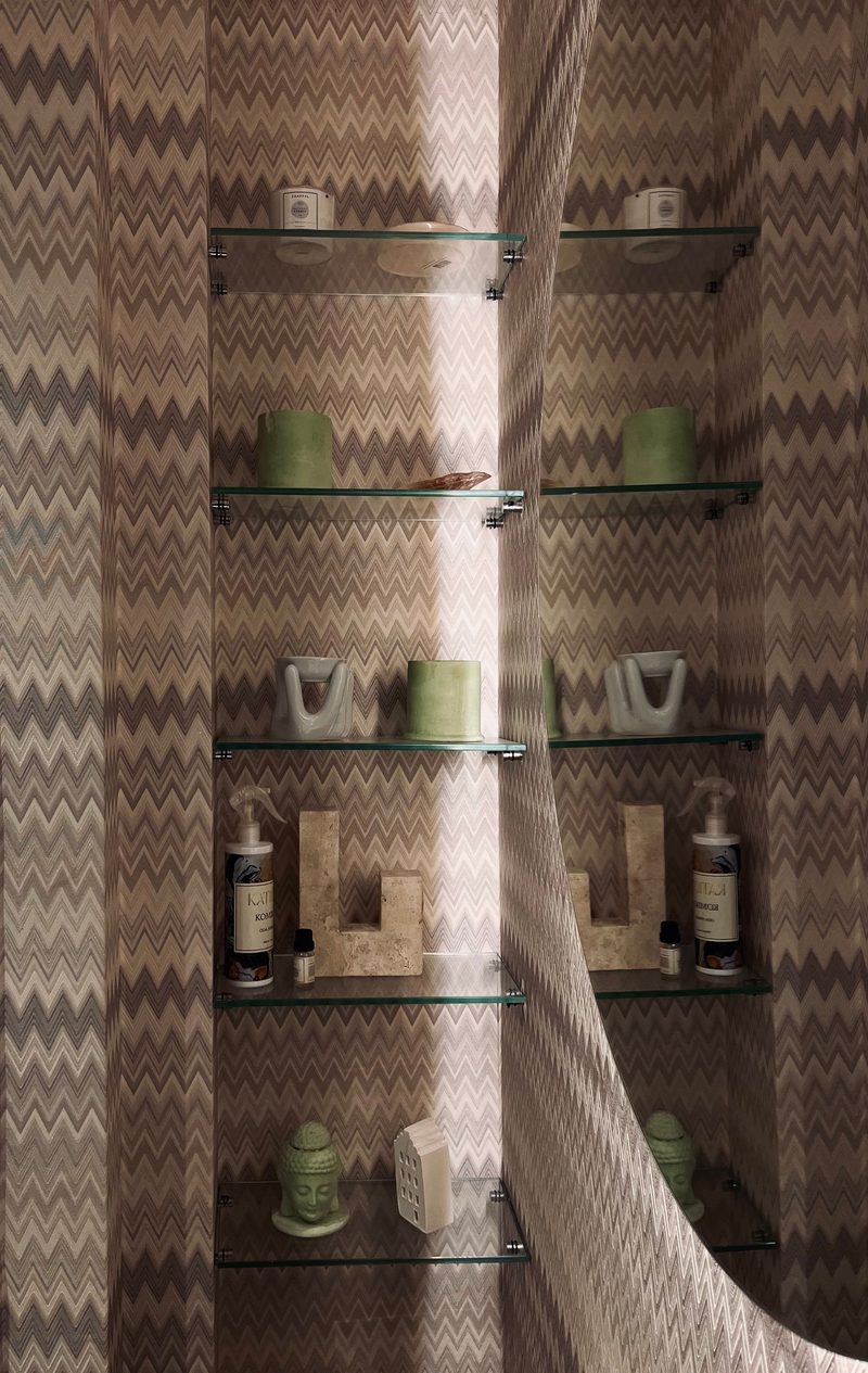 Bathroom detail with a bold zigzag chevron wallpaper behind minimalist glass shelves